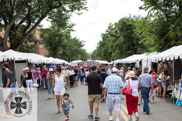 A street view of the Contemporary Indian Market in Santa Fe, NM, with artists' booth lining both sides of the street and attendees walking and shopping