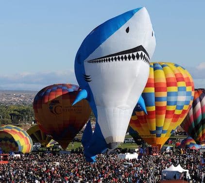 A display of colorful hot-air balloons at the Albuquerque International Balloon Fiesta. One of them is shaped like a shark.