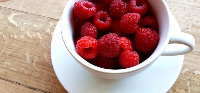 A coffee cup filled with fresh raspberries