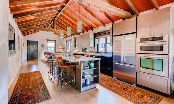 The kitchen of a Santa Fe home with exposed rafters in the ceiling and high-end stainless steel appliances