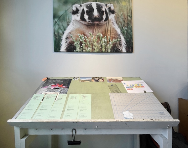 A badger print on the wall with a workspace desk below it