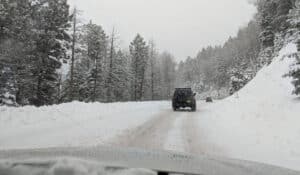 A car driving down a snowy road in Santa Fe, New Mexico, after a winter snowfall