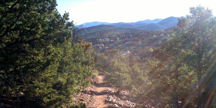 A trail at the Dale Ball Trails in Santa Fe, New Mexico, with a view of mountains in the background