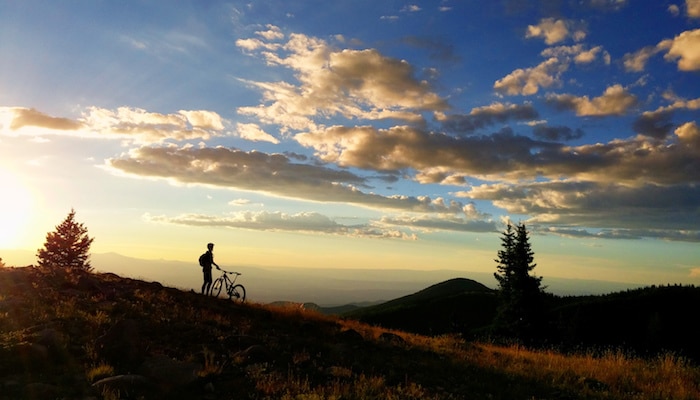 A cyclist pauses beside his mountain bike to take in the magnificence of a Santa Fe sunset