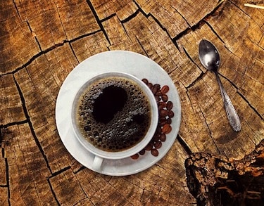 Cup of coffee and coffee beans on slab of wood