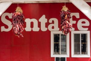 Two strings of red chiles hang in front of a sign that says "Santa Fe."