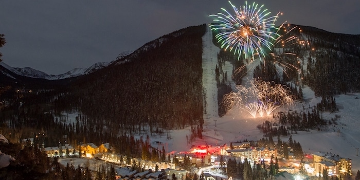 Fireworks exploding in the night sky at Taos Ski Valley in Santa Fe, New Mexico. The town is visible at the base of the mountain.