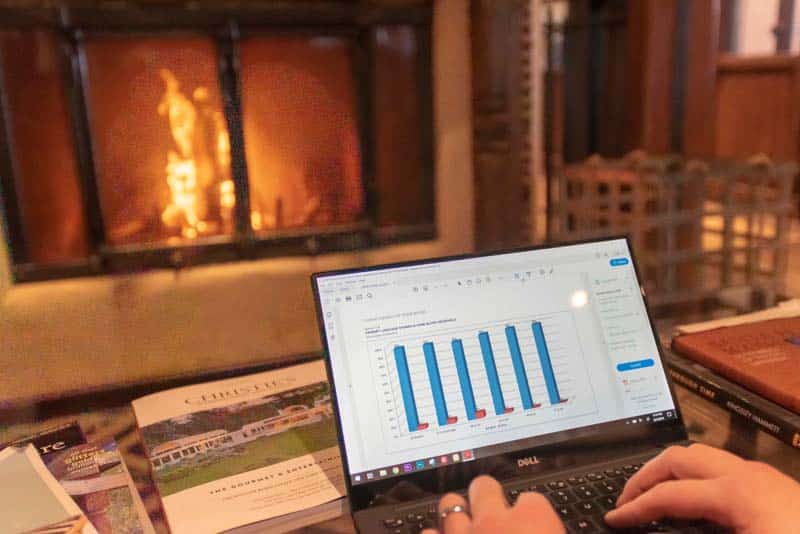 A view of someone working from home on a laptop in front a fireplace