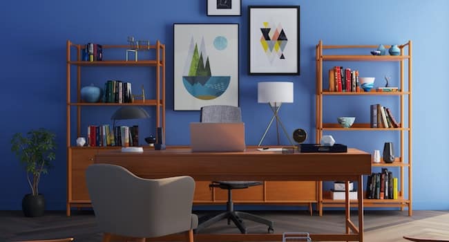 A home office decorated with a teak desk, teak bookcases, and artwork on the wall