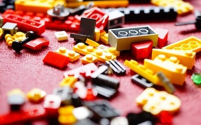 Loose LEGO blocks scattered on a pink carpet