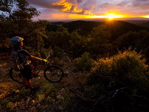 A cyclist takes in a breath-taking view of the sunset over mountains in Santa Fe
