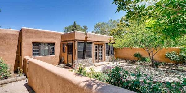 The exterior of a Santa Fe home with a front yard enclosed by adobe walls