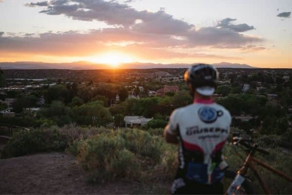 A mountain biker watches the sunset over Santa Fe, New Mexico