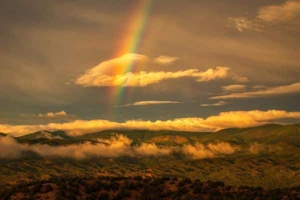 A rainbow over a view of sky, clouds, and mountains in Santa Fe, New Mexico