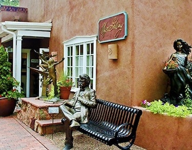 A statue sitting on a park bench in downtown Santa Fe