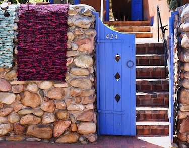 Front entrance to a Santa Fe home with a blue gate and stonewall