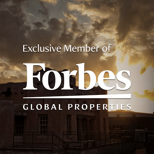 Forbes Global Properties exclusive member logo with Gross Kelly & Co building in the back ground with a stunning sunset