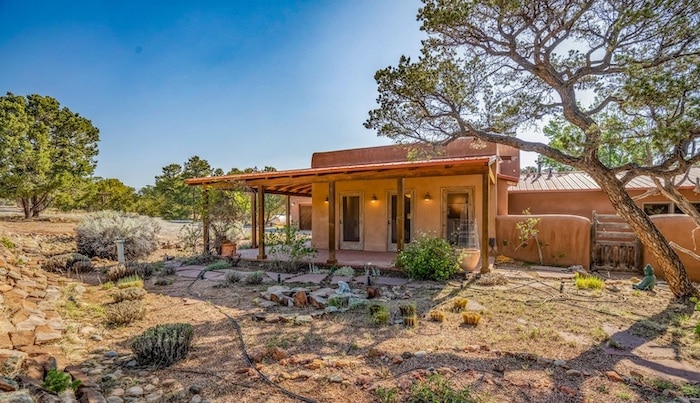 Exterior view of 6 Apache Point, Santa Fe, listed exclusively by Barker Realty, featuring traditional adobe-style architecture and naturalized landscaping