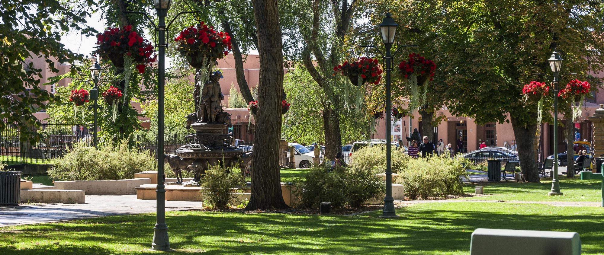 Cathedral Park in downtown Santa Fe. Shade trees, green grass, and statue.