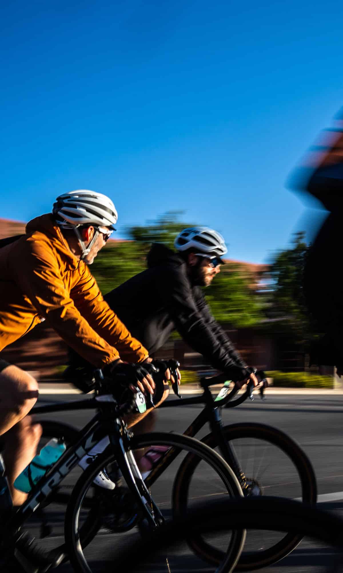 Two road cyclists cruising with a blurry background behind them.