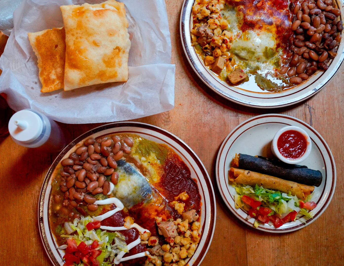 Three plates of food featuring New Mexican red and green chile, flautas, and sopapillas.