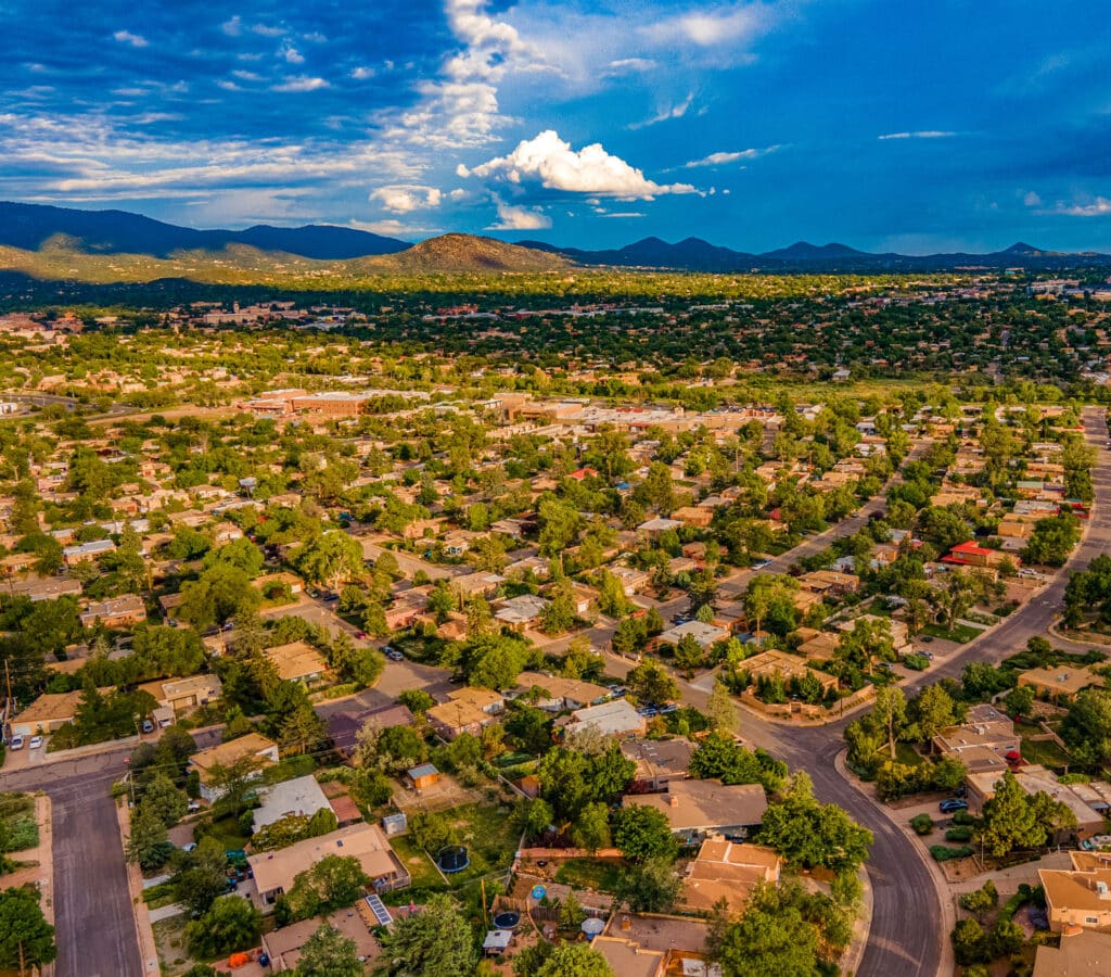Aerial view of streets and houses looking toward horizon of foothills and sky in Santa Fe, NM.